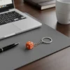 dice-keychain-laptop-computer-sitting-on-a-desk-with-a-keychain-and-a-pen