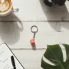 dice-keychain-there-is-a-notepad,-pen,-camera,-and-a-cup-of-coffee-on-a-table